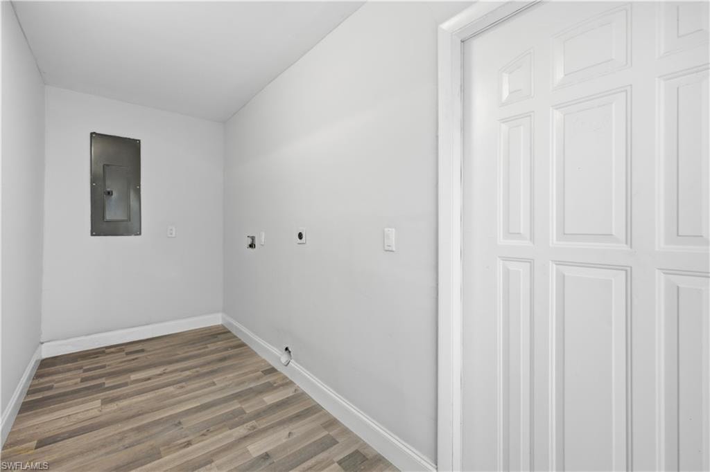 Dedicated utility area featuring wood-finish flooring, white baseboards, and a paneled door