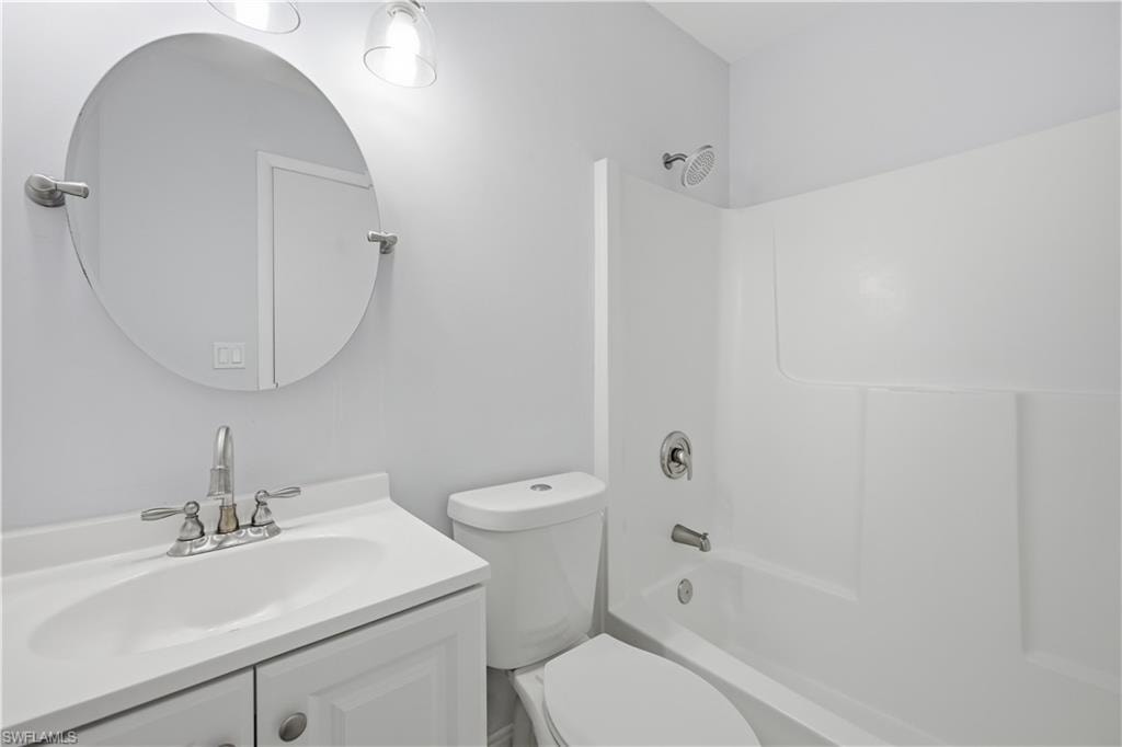 Full bathroom featuring a white vanity with integrated sink, chrome faucet, and a round wall-mounted mirror