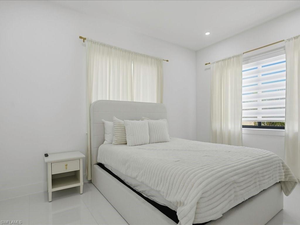 Bright room featuring recessed lighting, a window with horizontal blinds and sheer curtains, and tile flooring