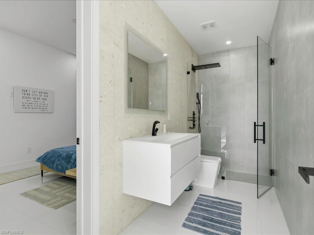 Full bathroom featuring a floating white vanity with integrated sink, black matte faucet, and a frameless glass shower enclosure