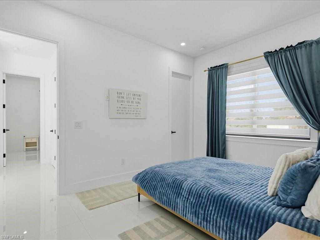 Bright room featuring large format tile flooring, a window with horizontal blinds, and recessed lighting