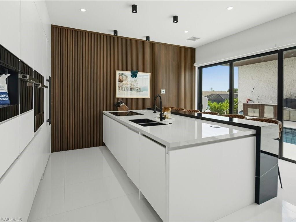 Contemporary kitchen featuring an expansive center island with integrated sinks and a matte black faucet