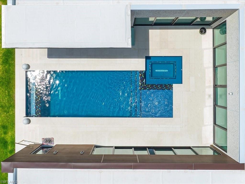 Outdoor leisure space featuring a rectangular swimming pool, integrated spa, and a modern fire pit