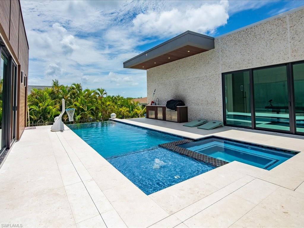 Outdoor living area featuring a large swimming pool with an integrated spa