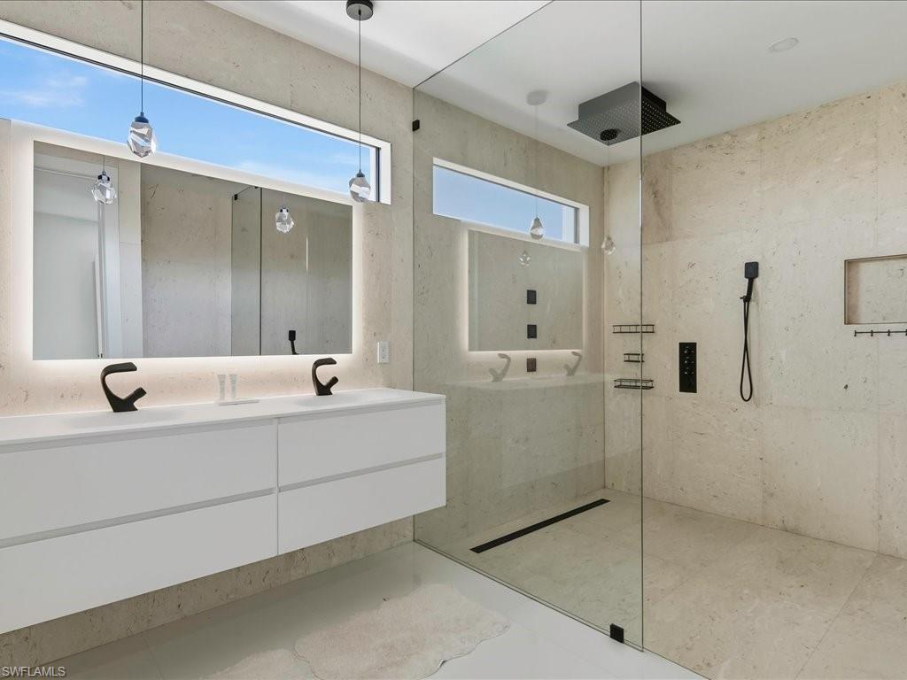 Floating double vanity with integrated sinks, back-lit mirror, and matte black fixtures