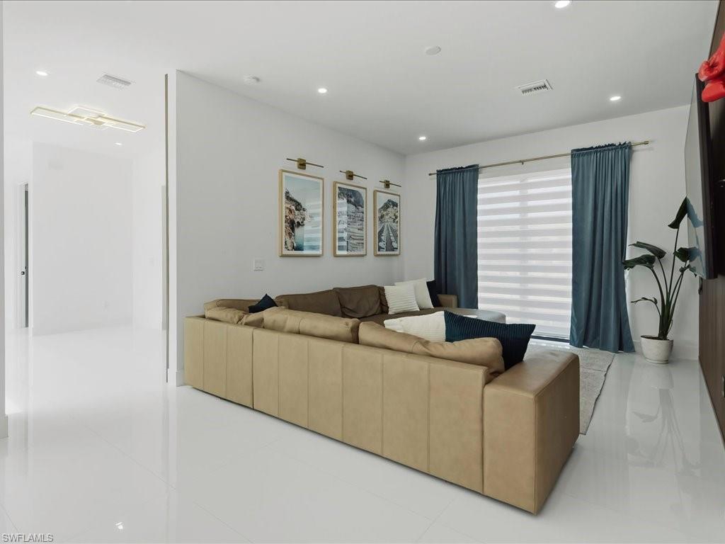 Living area featuring polished tile flooring, recessed lighting, and a large window with privacy blinds