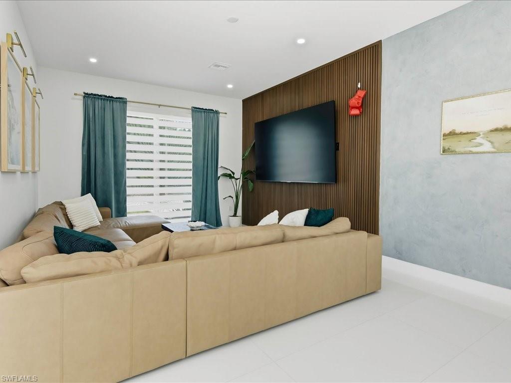 Living area featuring a slat wood accent wall, mounted television, and recessed lighting