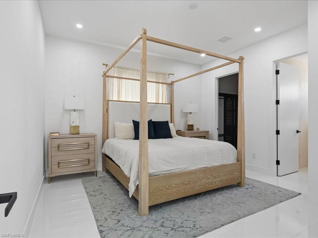 Spacious bedroom featuring recessed lighting, bright white walls, and sleek white flooring
