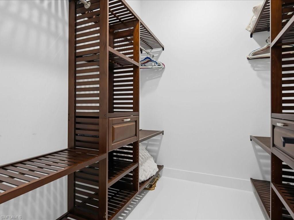 Built-in closet organization system featuring rich wood-finish shelving, integrated drawers with metal hardware, and hanging rods