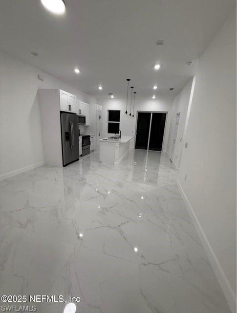 Unfurnished living room featuring light marble finish floors and recessed lighting