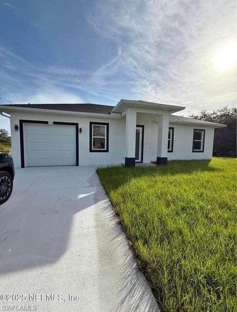 View of front facade with driveway, a front yard, an attached garage, and stucco siding