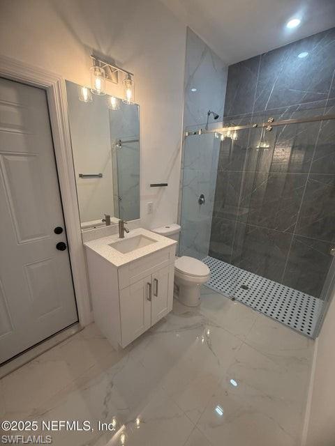 Full bathroom featuring a marble finish shower, vanity, light marble finish flooring, and recessed lighting