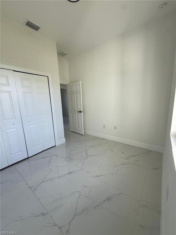 Unfurnished bedroom featuring light marble finish flooring and a closet