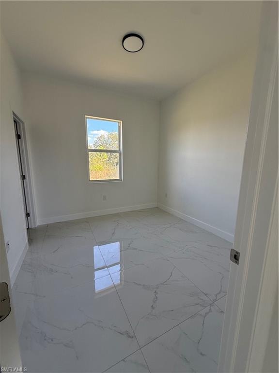 Spare room featuring light marble finish floors and baseboards