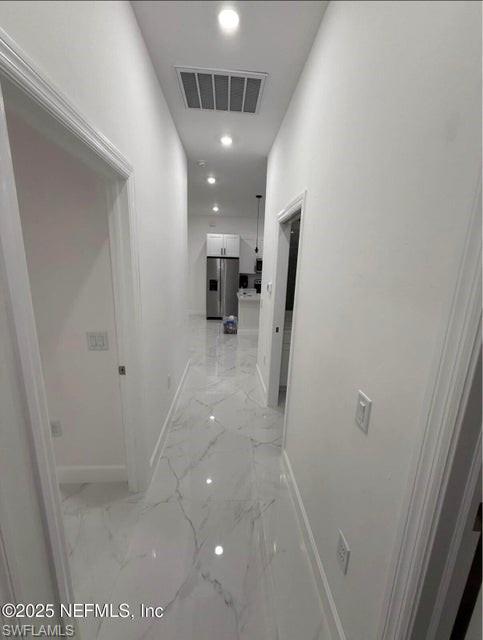 Corridor featuring recessed lighting and light marble finish floors