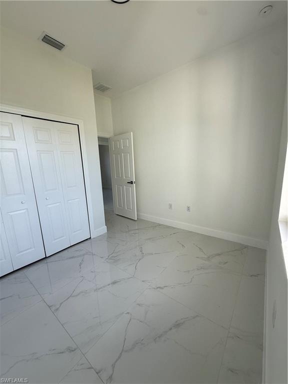 Unfurnished bedroom featuring light marble finish flooring and a closet