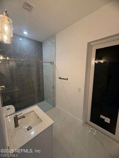 Bathroom with light marble finish flooring, a marble finish shower, vanity, and recessed lighting