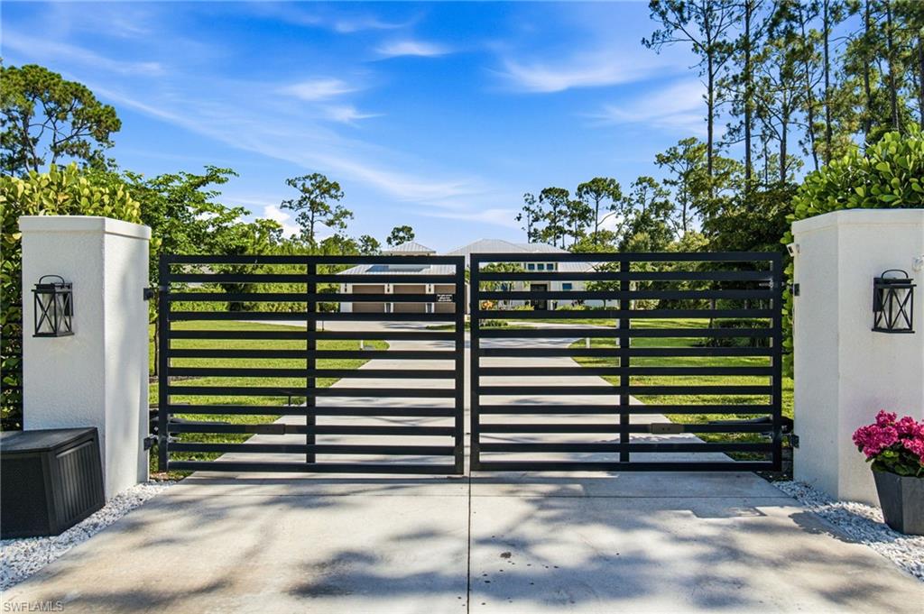 Custom motorized luxury  Gated Entry is enhanced with tropical landscaping details and neatly maintained hedgerow across the frontage.