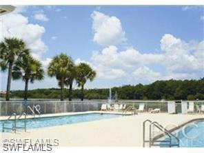 Outdoor swimming pool with integrated spa, surrounded by a concrete deck and metal fencing