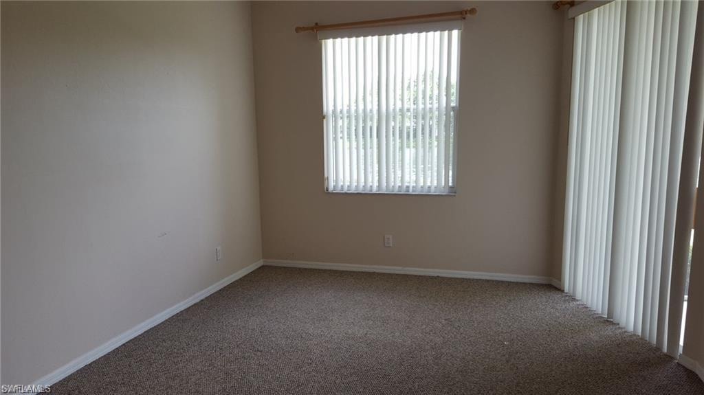 Carpeted room featuring a window with vertical blinds and a sliding glass door with vertical blinds