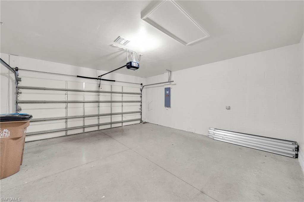 Spacious garage featuring a concrete floor, automatic garage door opener, and a wall-mounted electrical panel