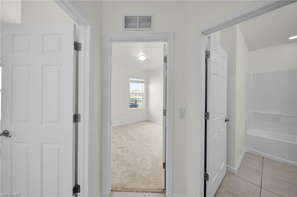 Bright hallway featuring a paneled door, light-colored walls, and tile flooring