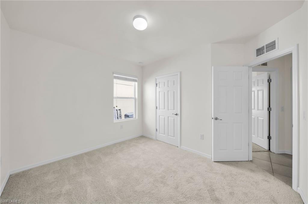 Carpeted room with a single window and neutral-toned walls