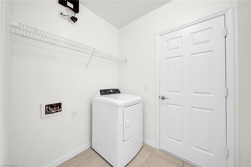 Laundry area featuring tile flooring, white walls, and a built-in wire shelf