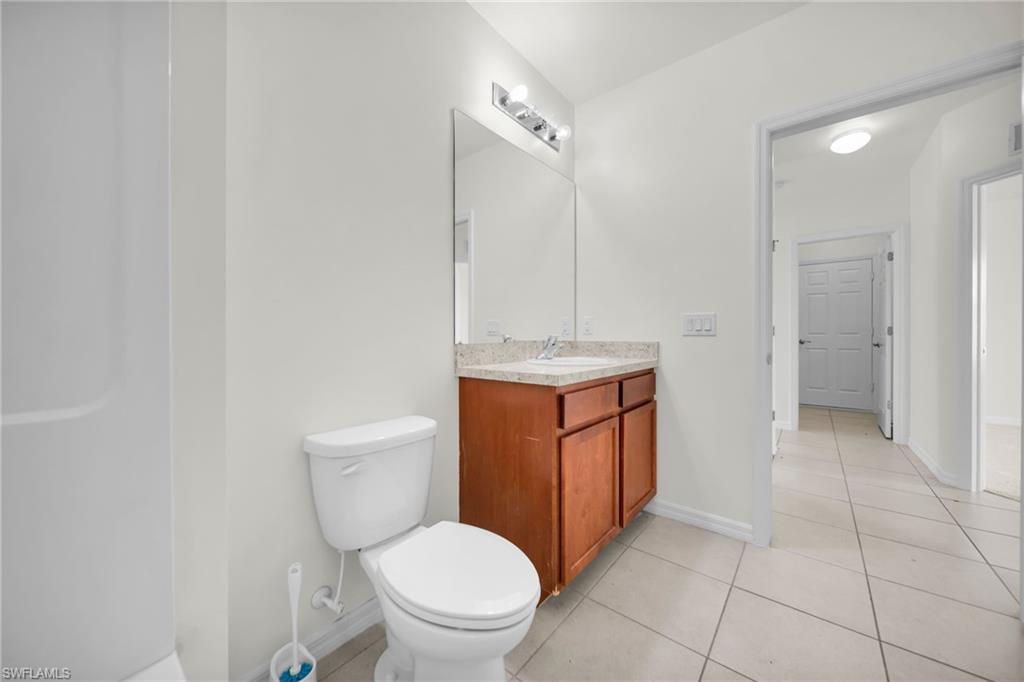 Bathroom featuring a wood-finish vanity with a light-colored countertop, an integrated sink, and a framed mirror with overhead lighting