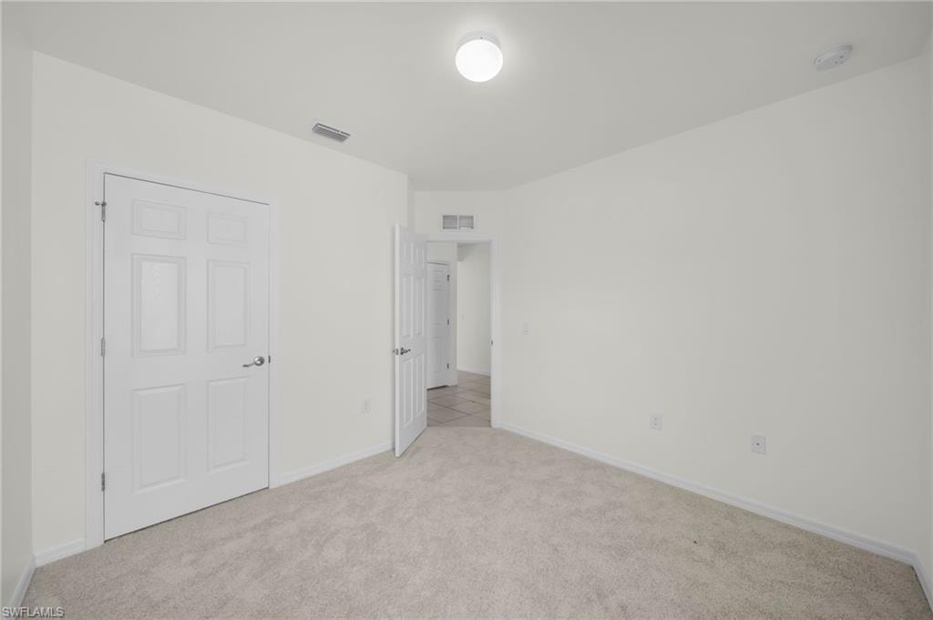 Spacious room featuring light-colored carpeting and white walls