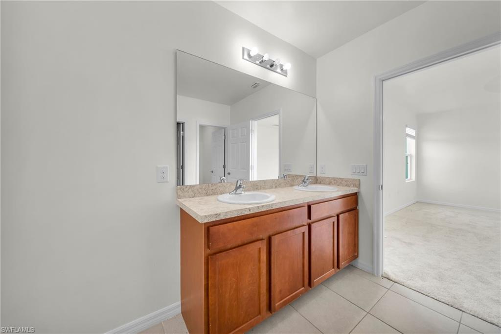 Dual-sink vanity featuring a light-colored countertop and wood-finish cabinetry