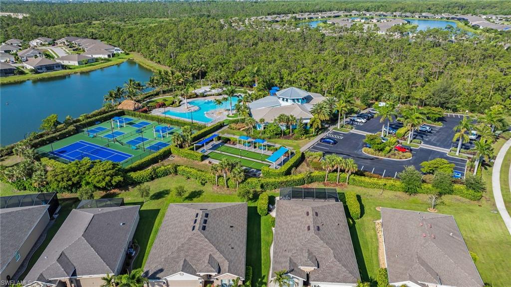 Community amenities featuring multiple pickleball courts, a resort-style swimming pool, a clubhouse building, and a parking area