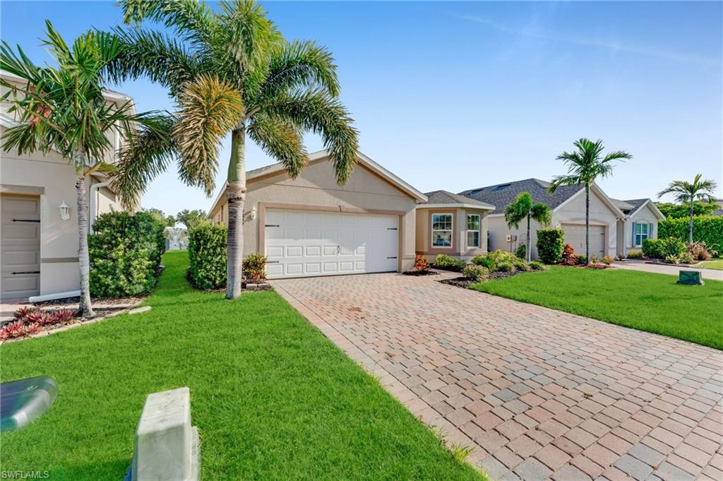 Single-story residence featuring a two-car garage, paver driveway, and a light-colored stucco exterior