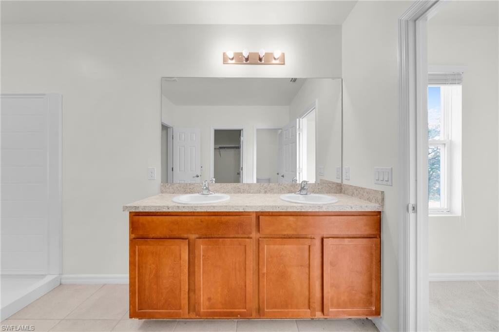 Dual vanity with light wood-finish cabinetry, integrated sinks, and a large wall-mounted mirror