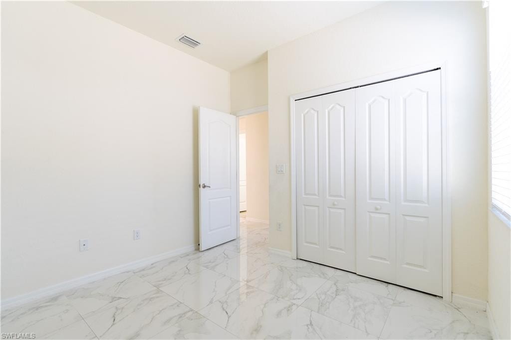 Bright interior featuring marble-look tile flooring, white bi-fold closet doors with decorative panels, and a white interior door