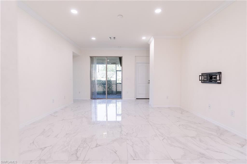 Spacious room featuring large format marble-look tile flooring, crisp white walls, recessed lighting, and crown molding