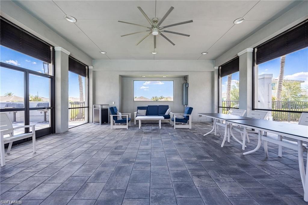 Covered patio featuring a large ceiling fan, recessed lighting, and expansive window walls with roller shades
