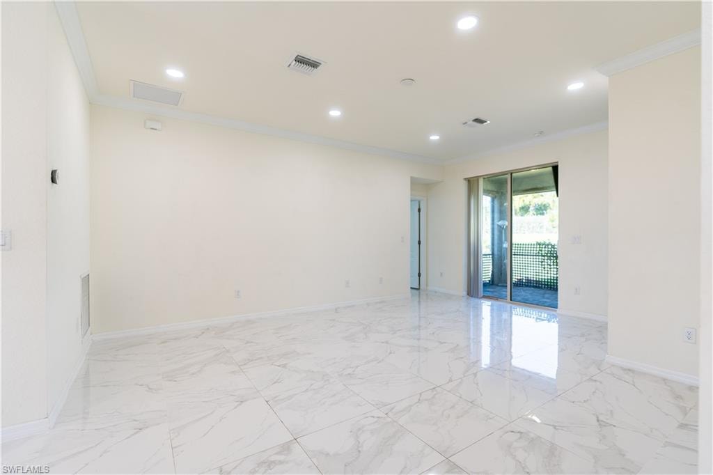 Spacious room featuring large format tile flooring, crown molding, recessed lighting, and sliding glass doors opening to an outdoor area