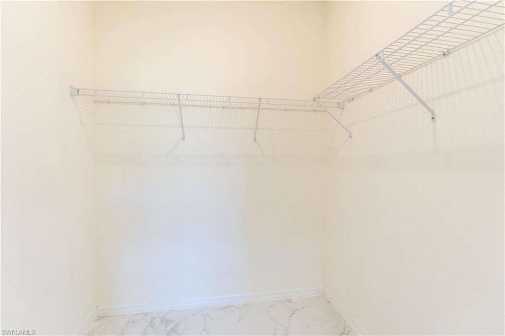 Walk-in closet featuring wire shelving, light-toned walls, and marble-look flooring
