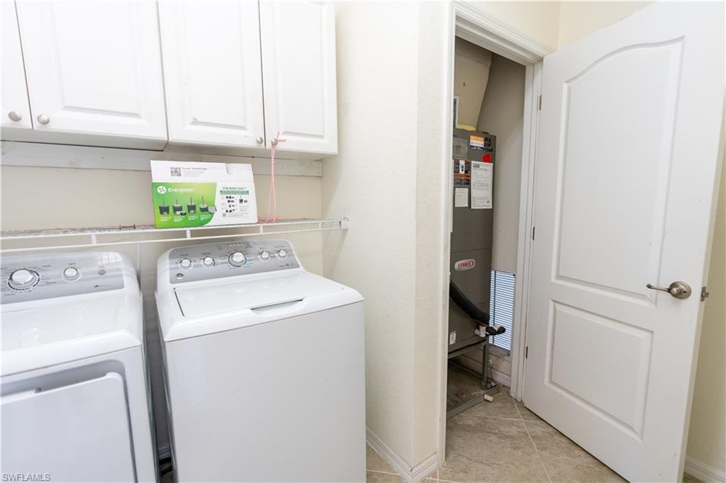 Utility space featuring white cabinetry, a wire shelf, and neutral floor tile