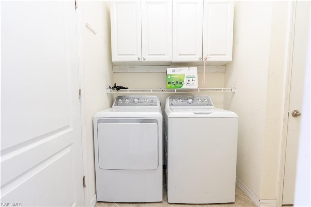 Dedicated laundry space featuring upper cabinetry, a wire storage shelf, and light-toned flooring