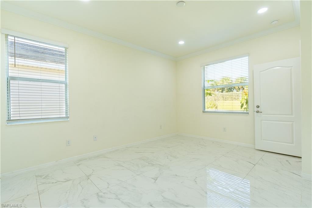 Spacious room featuring large format marble-look tile flooring, two windows with horizontal blinds, recessed ceiling lighting, and crown molding