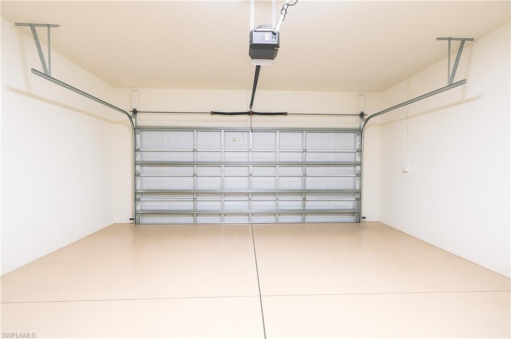 Spacious two-car garage featuring a light-toned epoxy floor, white painted walls, and an automatic garage door opener system