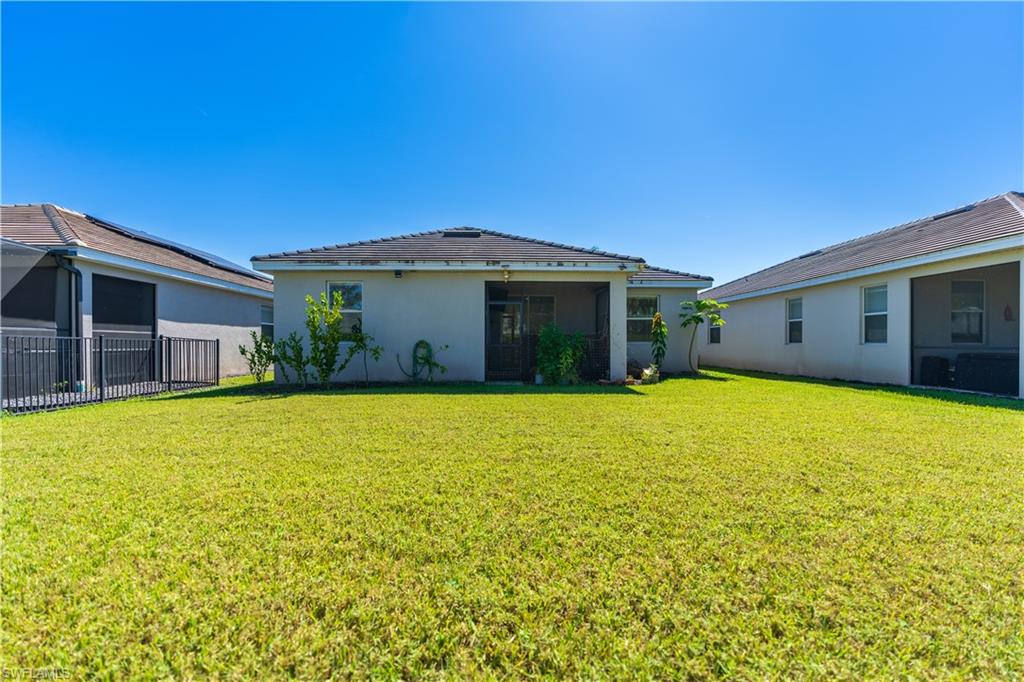 Expansive green lawn with a screened patio, rear home exterior, and mature landscape plantings