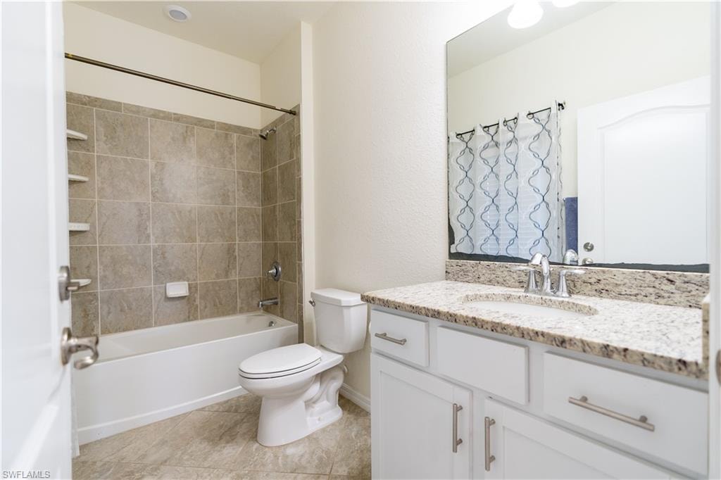 Bathroom featuring a white vanity with a granite countertop, undermount sink, and brushed nickel hardware