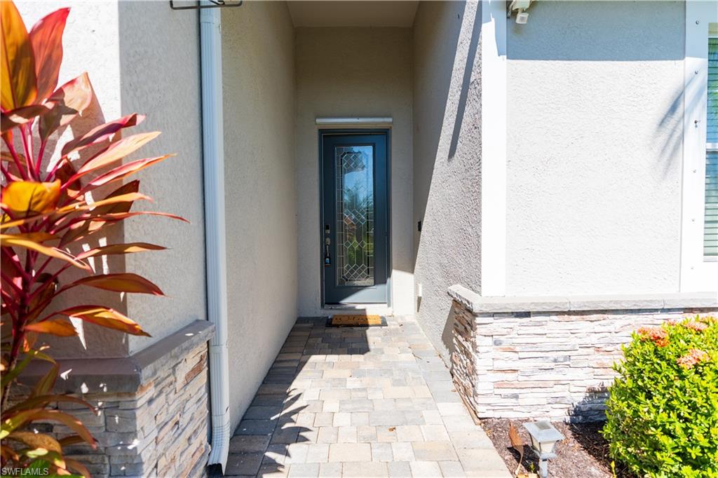 Paver walkway leading to a decorative glass entry door
