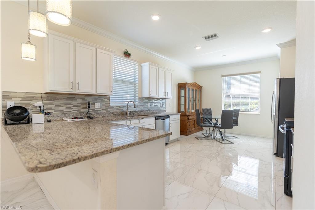 Kitchen featuring light-toned cabinetry, a mosaic tile backsplash, and granite countertops