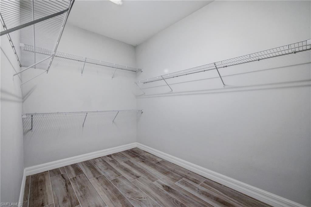 Spacious closet featuring wood-finish flooring, white baseboards, light gray walls, and wire shelving