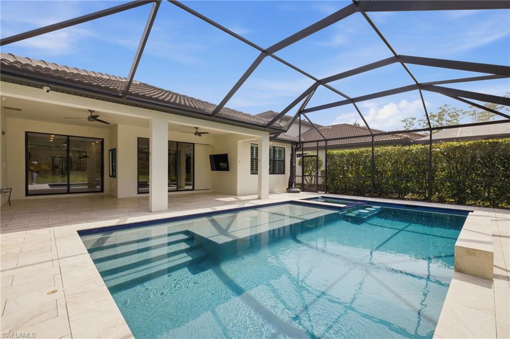 Screened-in outdoor pool area featuring a rectangular pool with integrated steps, a paver deck, and an expansive covered patio