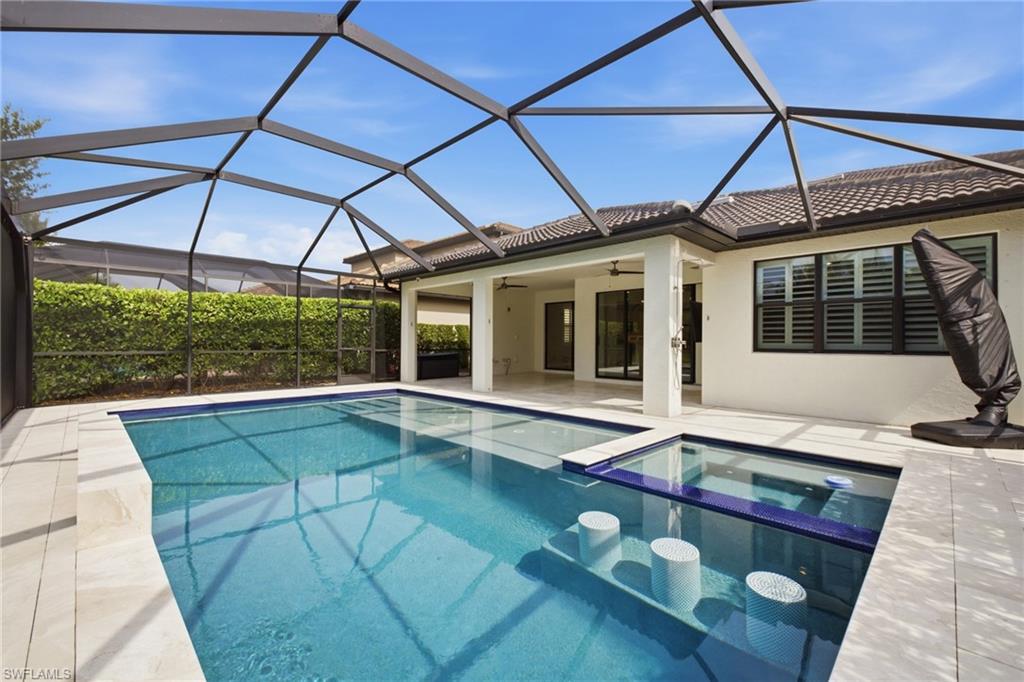 Screened pool enclosure featuring a rectangular pool with integrated spa and swim-up seating